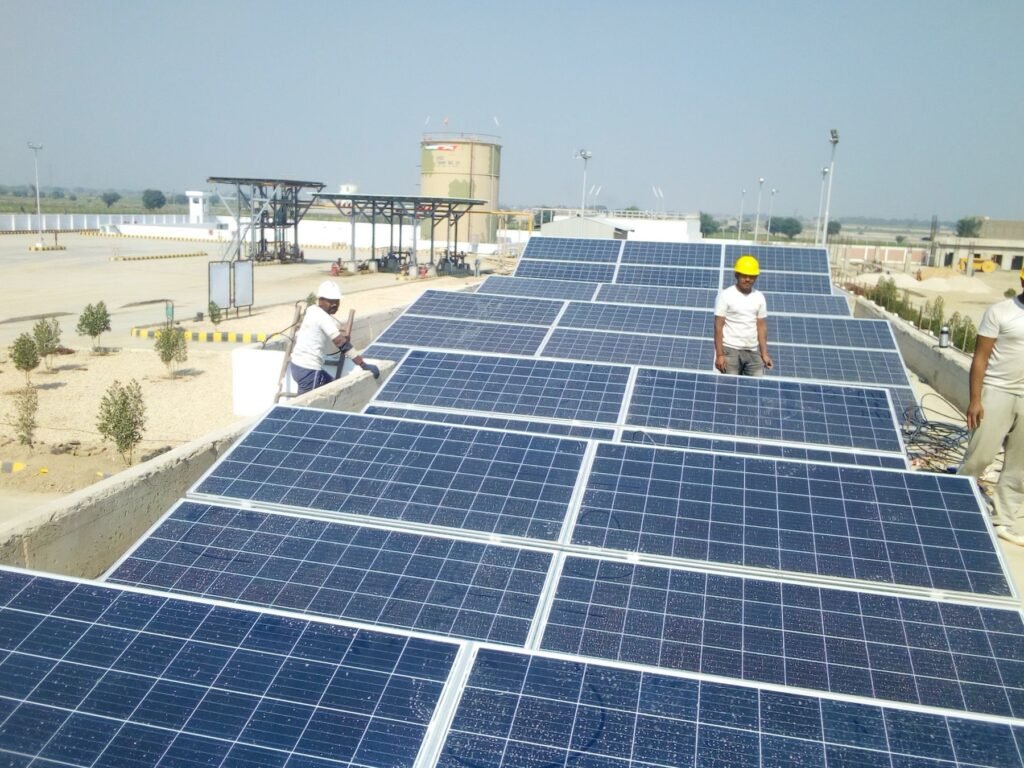 Installers fitting rows of solar panels on an industrial rooftop